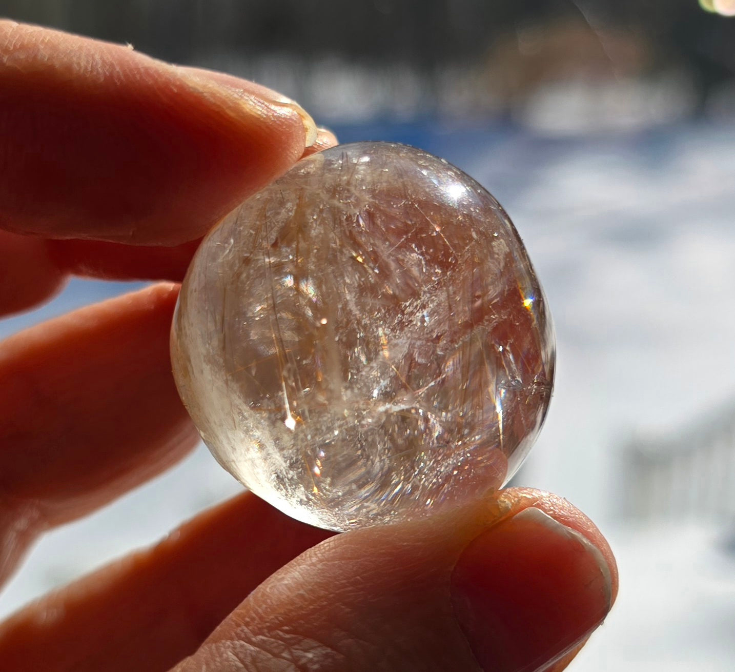 Clear Gold Rutilated Quartz Lens held against light