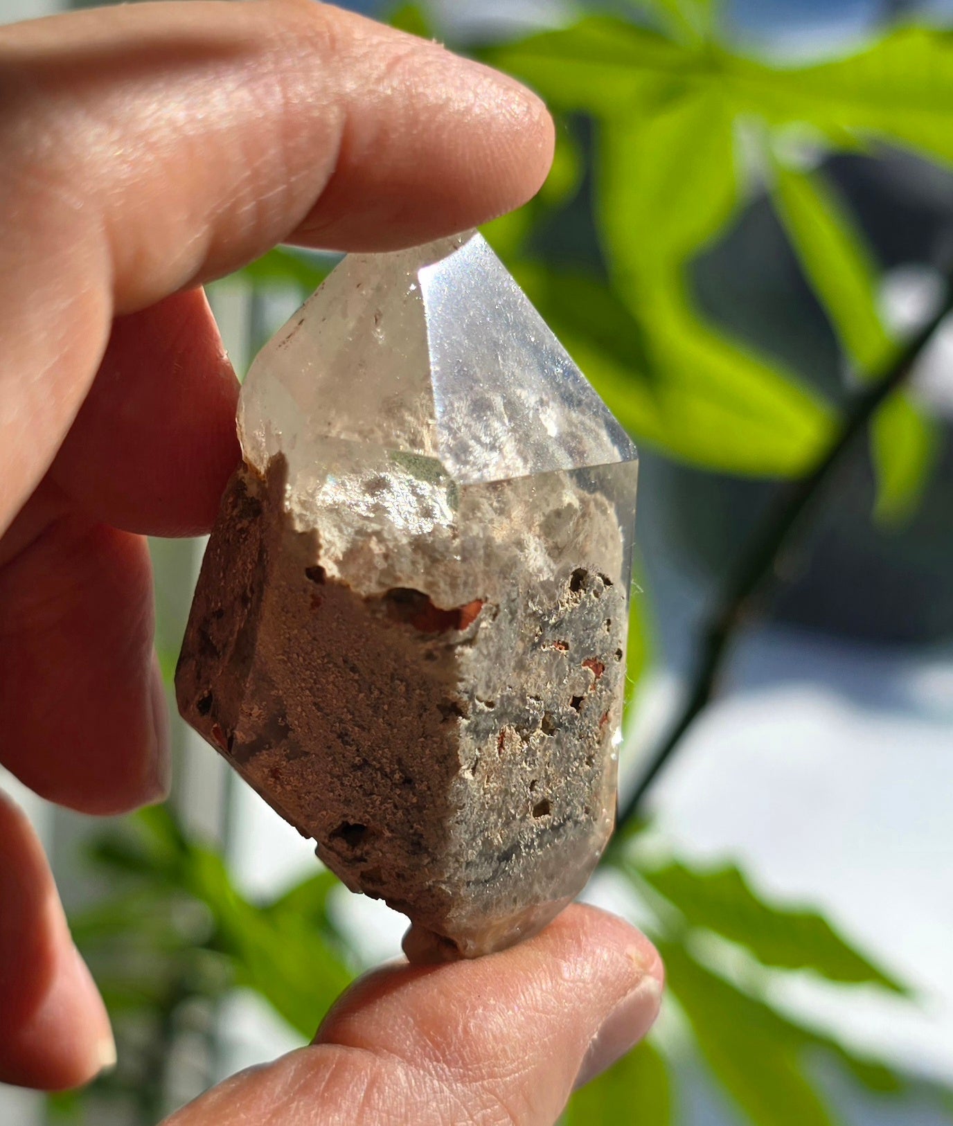 Hand holding polished Garden Quartz Free-Form Natural Lodolite Crystal outdoors